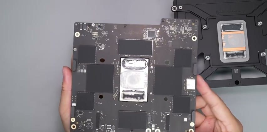 Scheda logica del Mac Studio con il chip M5 Max al centro coperto dal coperchio metallico, accanto al blocco di raffreddamento con la base in rame